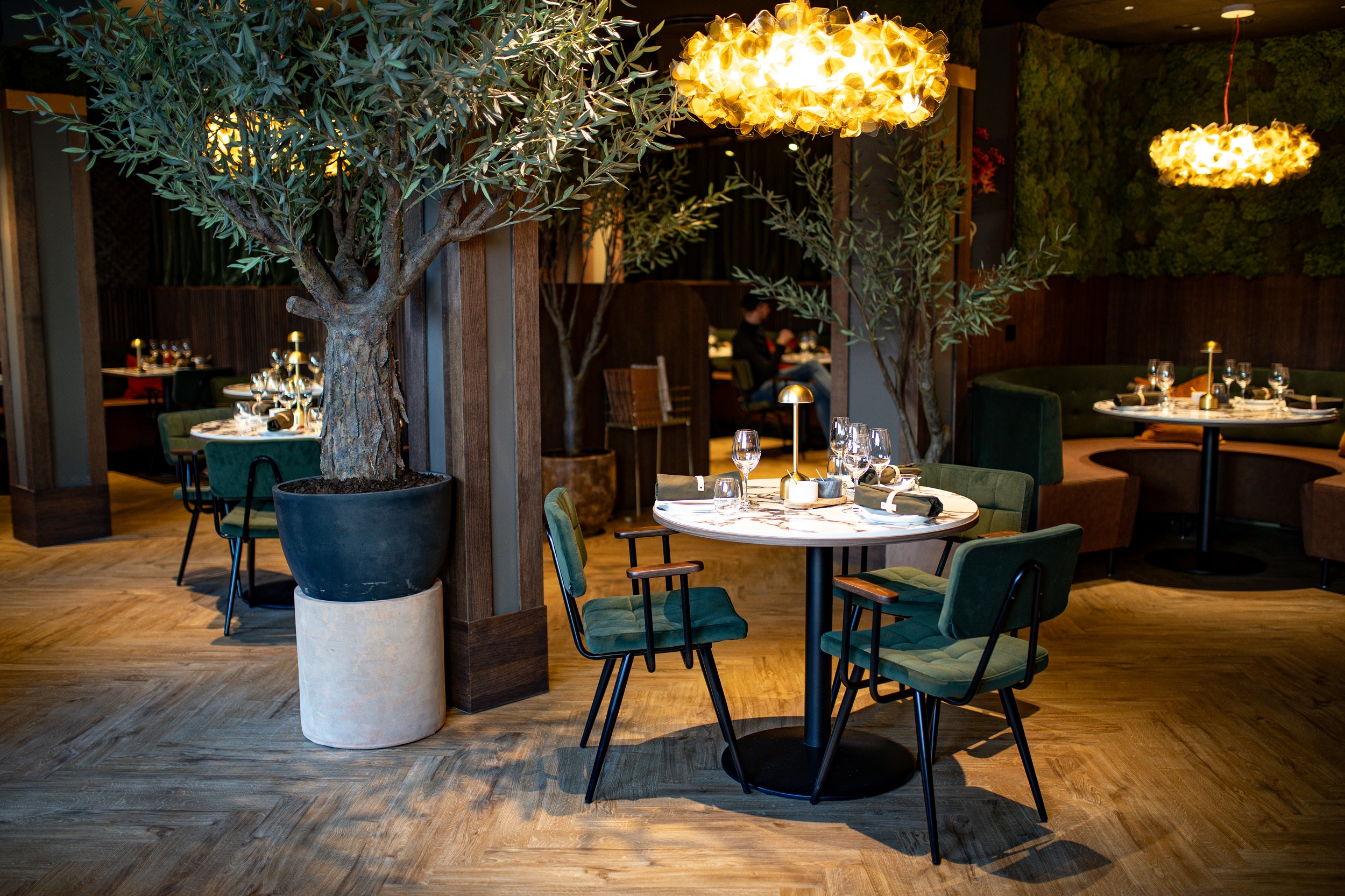 Basso Social Bergen dining room with warm pendant lighting and green chairs