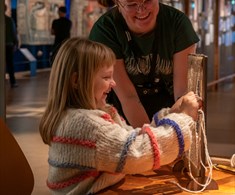 Museumsvert og barn vever